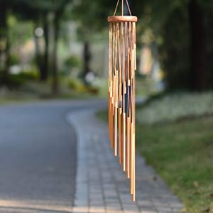 A 36-inch wind chime with wooden clapper and copper-brown tubes suspended from a circular wooden top, hanging outdoors.