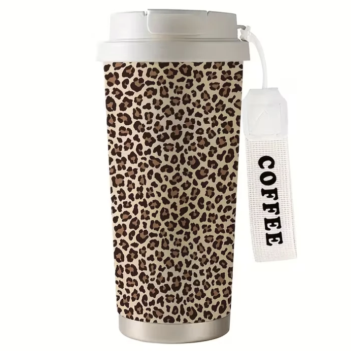 A reusable travel mug with a leopard print design, silver base, and white lid, featuring a coffee label attached by a loop.