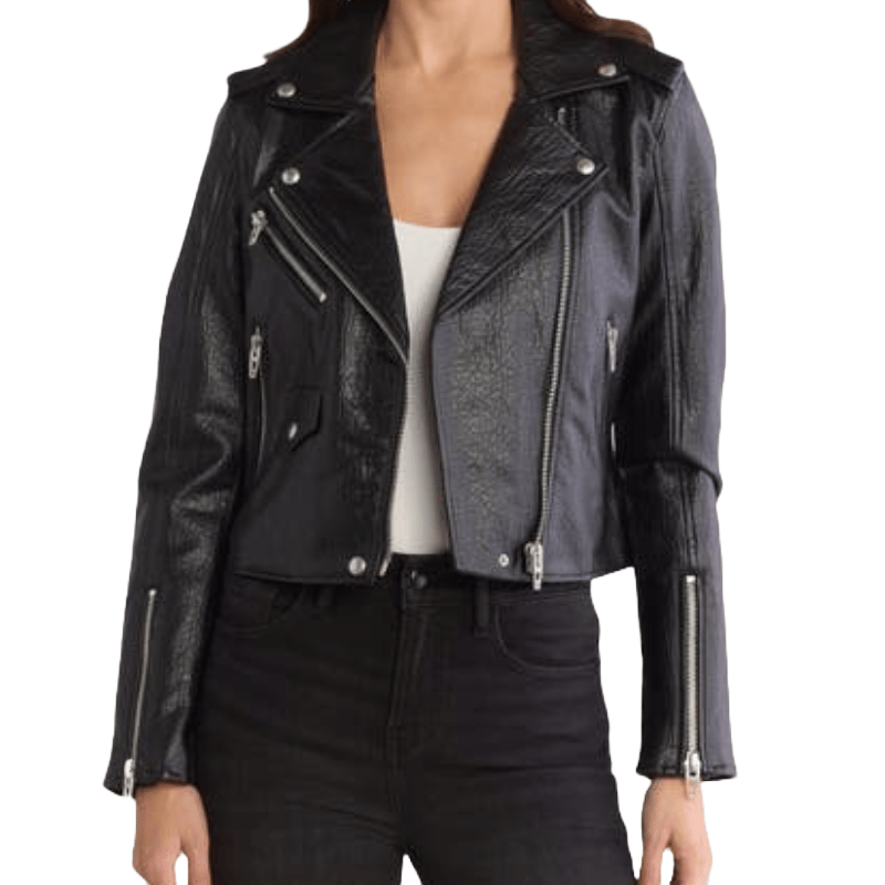 A cropped faux leather moto jacket with a notched lapel, silver-tone zip details, and snap-button accents. It features multiple zipped pockets and a sleek, slightly textured finish.