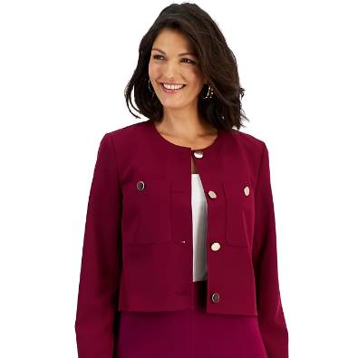 A woman wears a wine-colored, waist-length INC pocket jacket featuring a round neckline, long sleeves, and button accents on the front and pockets, layered over a white top.