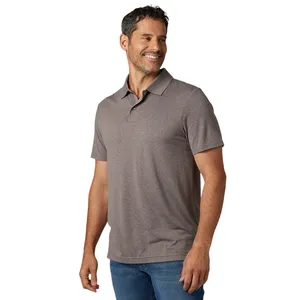 A man is wearing a short-sleeve, gray polo shirt paired with blue jeans, smiling to the side.