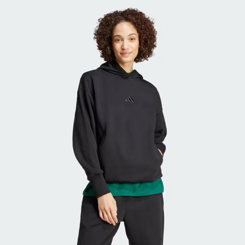 A woman is wearing a black Adidas fleece hoodie with long sleeves, ribbed cuffs, and the brand's logo on the chest.