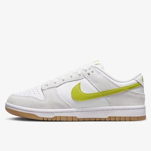 White Nike Dunk Low sneakers with a bright yellow Swoosh and a gum outsole.