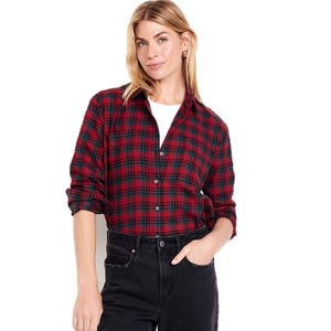 A woman wearing a red and black plaid button-up shirt over a white top, paired with black jeans.