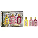 Gucci Flora gift set featuring three floral-themed perfumes in yellow, pink, and purple bottles, each with a gold cap, displayed against a floral background.