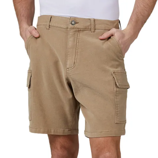 Tan cargo shorts with side pockets, belt loops, and a button closure, being modeled by a person with their hands in pockets.