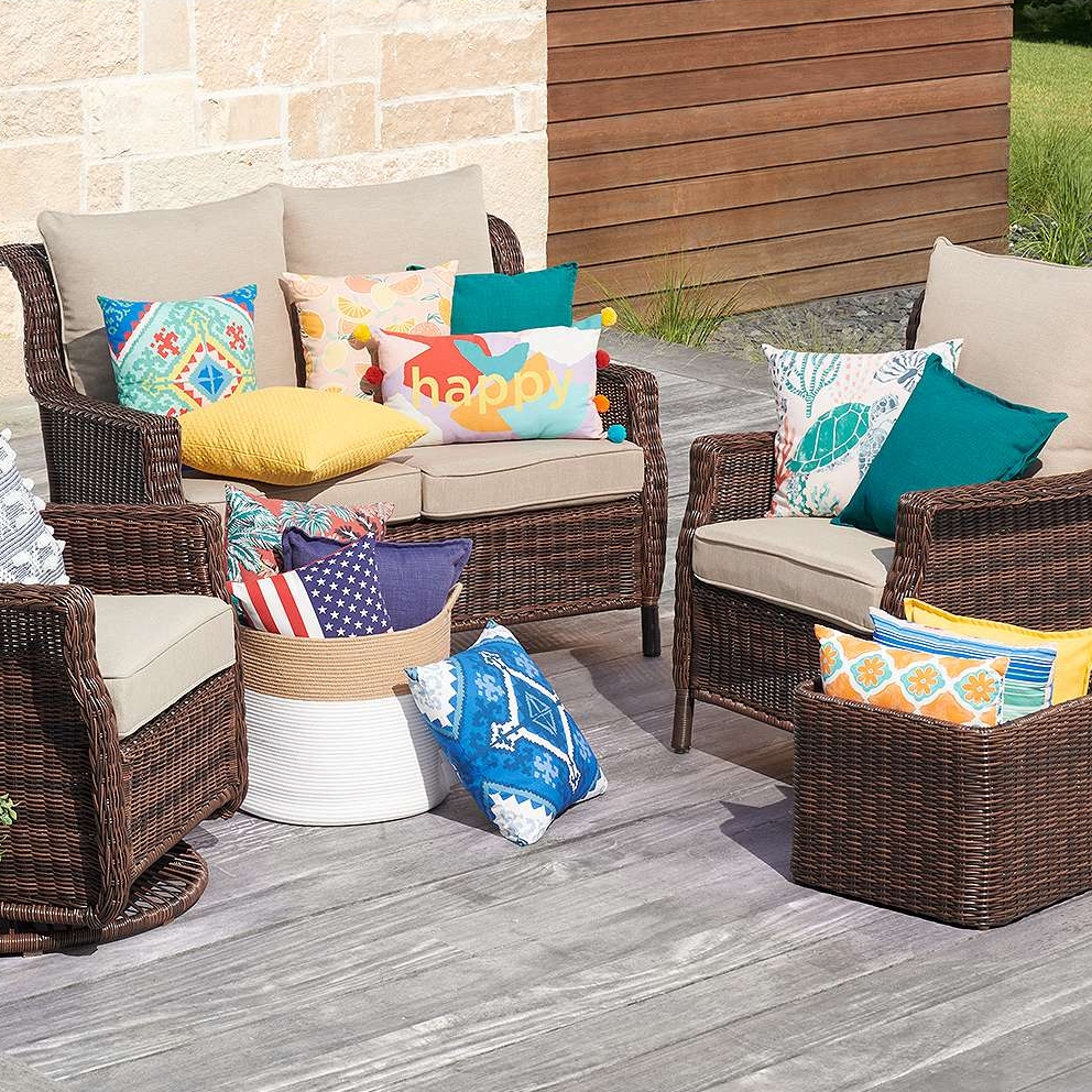 Outdoor wicker furniture set with cushions and colorful decorative pillows.