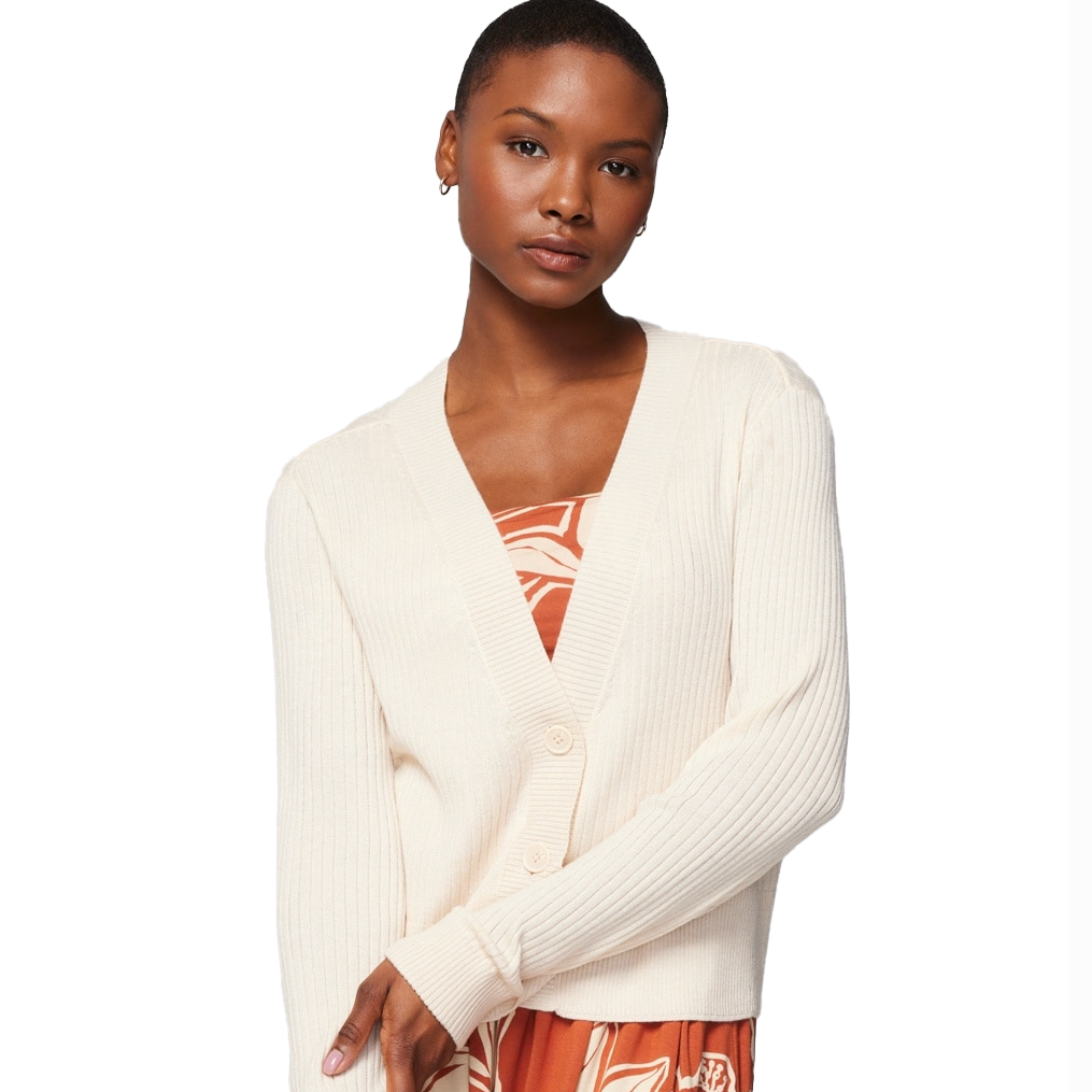 A cream-colored, ribbed cardigan with a V-neckline, long sleeves, and button closure, worn over an orange dress with a white abstract pattern.