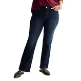 A person wearing dark blue bootcut jeans paired with black loafers and a red top.