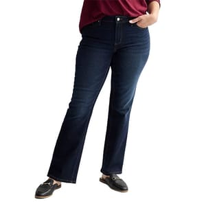 A person wearing dark blue bootcut jeans paired with black loafers and a red top.