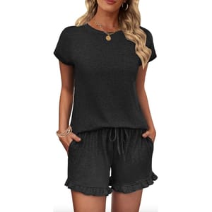 Black short-sleeve top and shorts set with ruffle detailing on the shorts, featuring a drawstring waist. Accessories include a gold necklace and bangles.