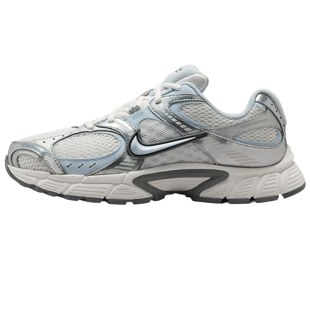 A white and light gray athletic sneaker with mesh panels and metallic accents, featuring a prominent black swoosh logo on the side and a textured sole for grip.
