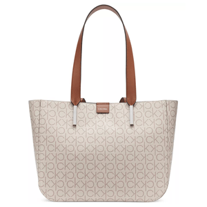 Calvin Klein Logo Medium Tote features beige fabric with an all-over \“CK\“ pattern, brown leather handles, and a small Calvin Klein logo tag at the top center.