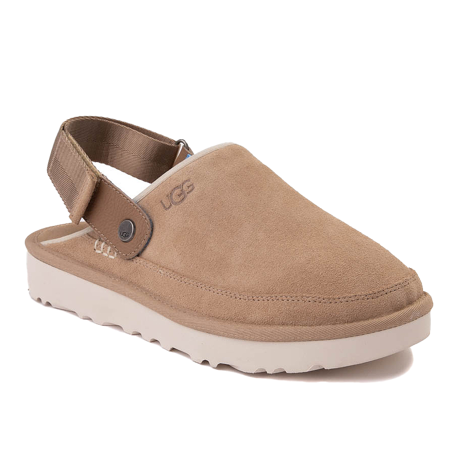 UGG Men's Suede Clogs feature a tan suede upper with a comfortable closed toe and a cushioned white sole. They include an adjustable brown strap with a button accent for a secure fit.
