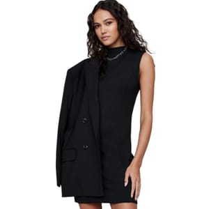 Sleeveless black mini dress with a fitted design and mock neck, paired with an oversized black blazer draped over one shoulder.