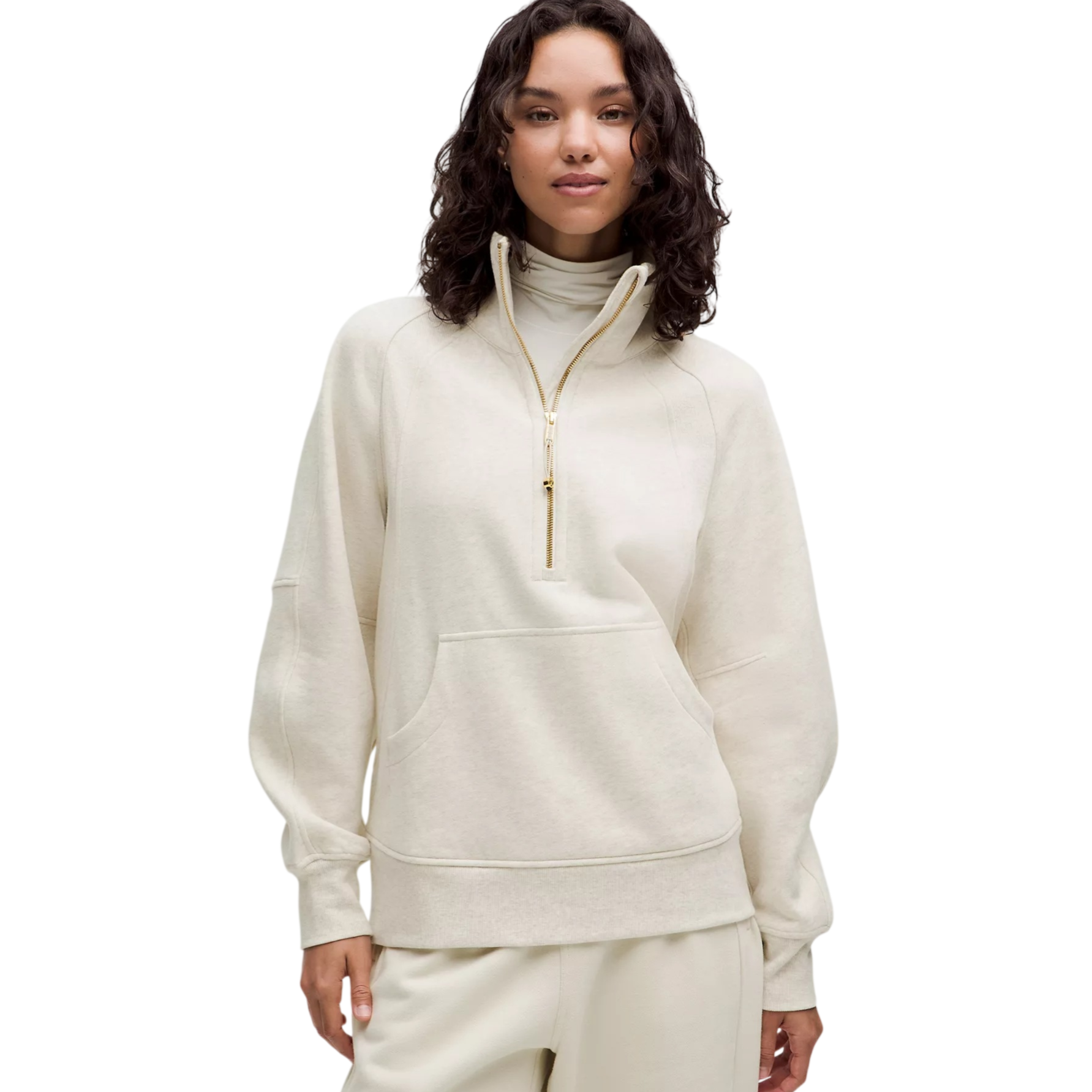 Woman wearing a cream-colored pullover with a half-zip closure, high collar, and front kangaroo pocket, paired with matching pants.
