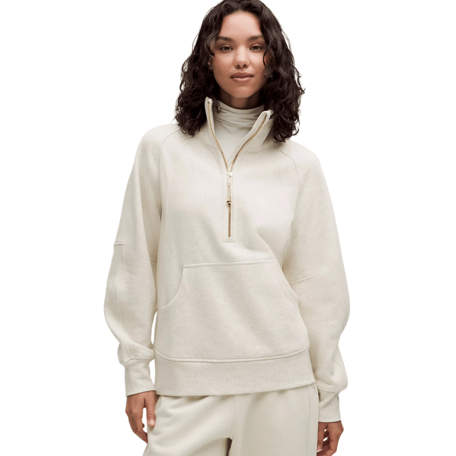 Woman wearing a cream-colored pullover with a half-zip closure, high collar, and front kangaroo pocket, paired with matching pants.