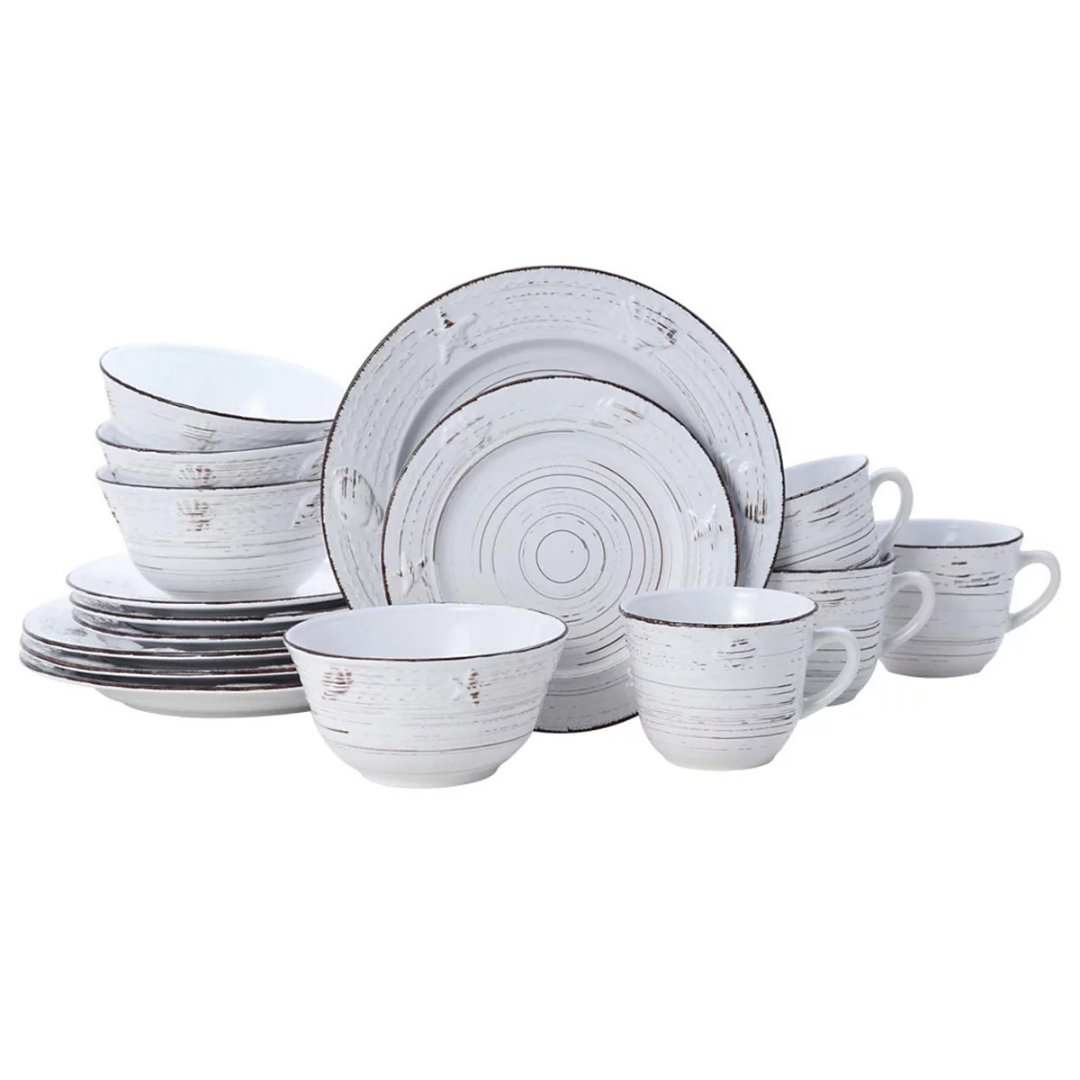 The 16-piece Pfaltzgraff Dinnerware Set features a rustic, textured design with white plates, bowls, and cups accented by a distressed look. The set includes four dinner plates, four salad plates, four bowls, and four mugs.