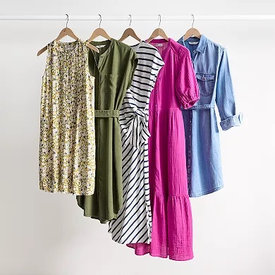 Five dresses on hangers, varying in color and pattern, including green, striped, floral, pink, and chambray.