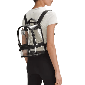 Lululemon's Clear Festival Backpack is a compact transparent backpack with black accents and adjustable straps, featuring the Lululemon logo on the front pocket. It's designed for easy visibility and convenience at events where clear bags are required.