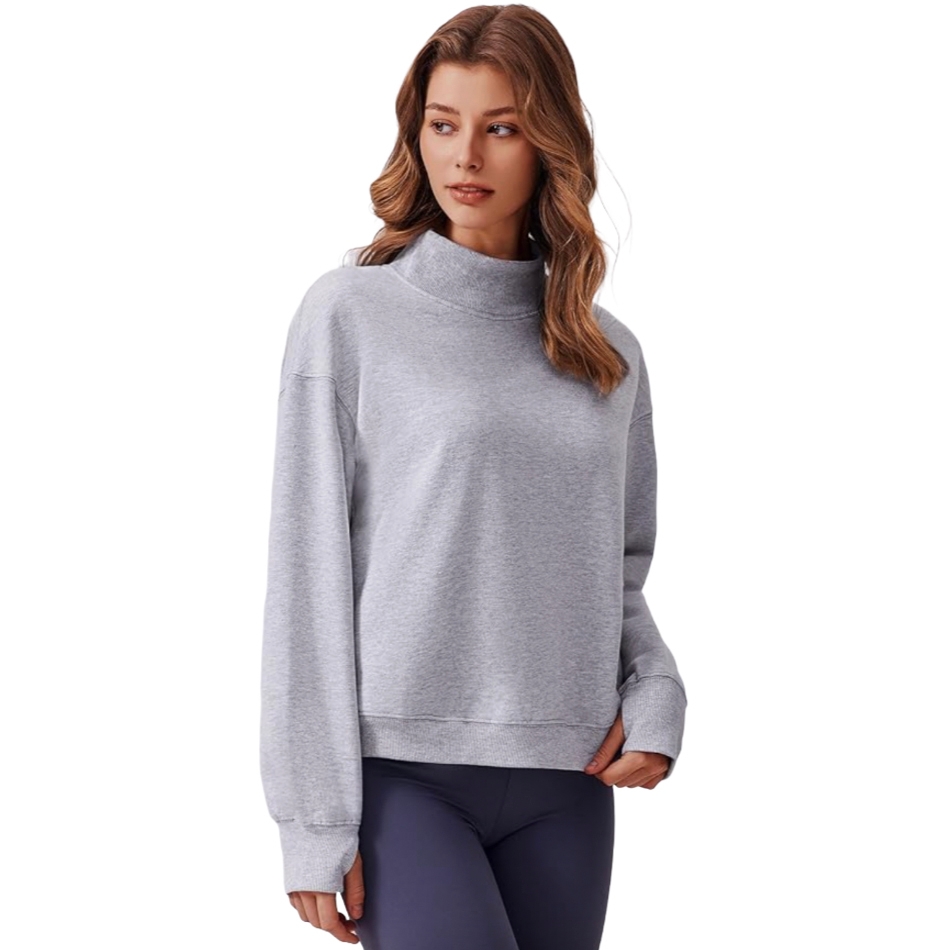 A woman is wearing a gray fleece top featuring a mock neck and thumb holes, paired with dark leggings. The top has a relaxed fit with long sleeves and ribbed cuffs.