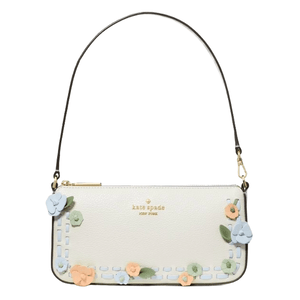 A white Kate Spade New York handbag adorned with colorful floral appliqués and a detachable black strap.