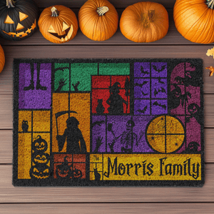 A Halloween-themed doormat featuring colorful blocks with silhouettes of spooky figures such as a skeleton, witch, bats, and pumpkins. Decorated with carved pumpkins on a wooden surface.