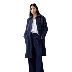 A woman wears a dark blue overcoat, white top, wide-legged denim pants, black belt, and black shoes, carrying a black bag on her shoulder.