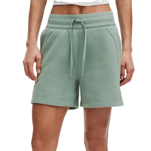 A person wearing light green drawstring shorts with an elastic waistband and side pockets.