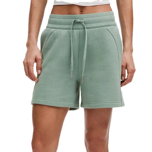 A person wearing light green drawstring shorts with an elastic waistband and side pockets.