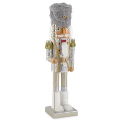A silver and white Christmas nutcracker soldier dressed in a glittery uniform with a faux fur hat and gold shoulder tassels.