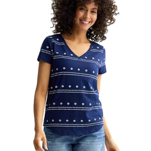 A woman is wearing a navy blue V-neck T-shirt with white dotted horizontal stripes, paired with blue jeans.