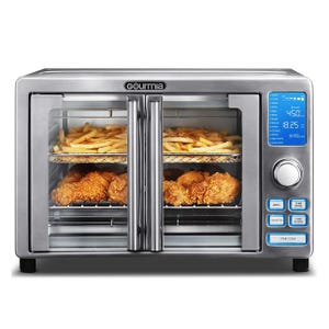 Gourmia air fryer oven with a digital control panel, featuring a double glass door design with trays of fries and fried chicken inside.