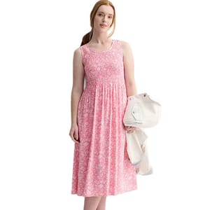 A woman wearing a sleeveless pink floral dress holds a white jacket draped over one arm.