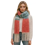 A woman is wearing a cozy, multicolored scarf with red, blue, and cream stripes, paired with a white sweater and blue jeans, standing in an urban setting.