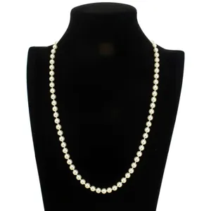 A single strand of white pearls is displayed elegantly on a black bust stand, showcasing a classic and timeless jewelry piece.
