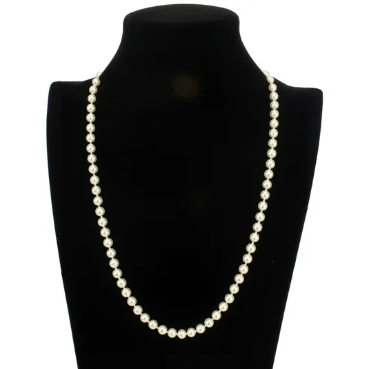 A single strand of white pearls is displayed elegantly on a black bust stand, showcasing a classic and timeless jewelry piece.