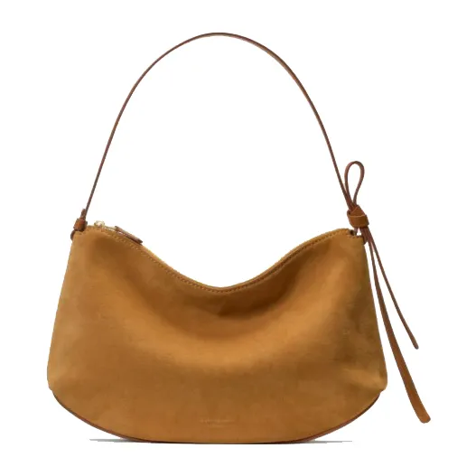 Tan suede handbag with a curved shape, featuring a thin strap and a decorative knot on one side.