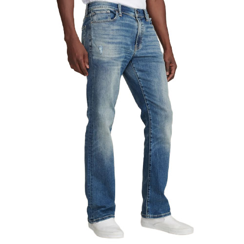 A person wearing light-wash straight-leg jeans paired with white slip-on shoes.