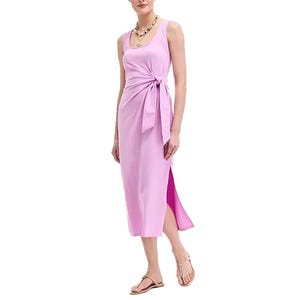 A sleeveless pink midi dress with a side slit and tie detail at the waist, paired with sandals and a necklace.