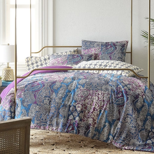A paisley patterned bedding set with blue and purple tones, including a comforter and matching pillows, displayed on a bed.