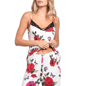 A woman wears a floral print pajama set with red and pink roses and purple butterflies, featuring a sleeveless top with black lace trim and matching pants.