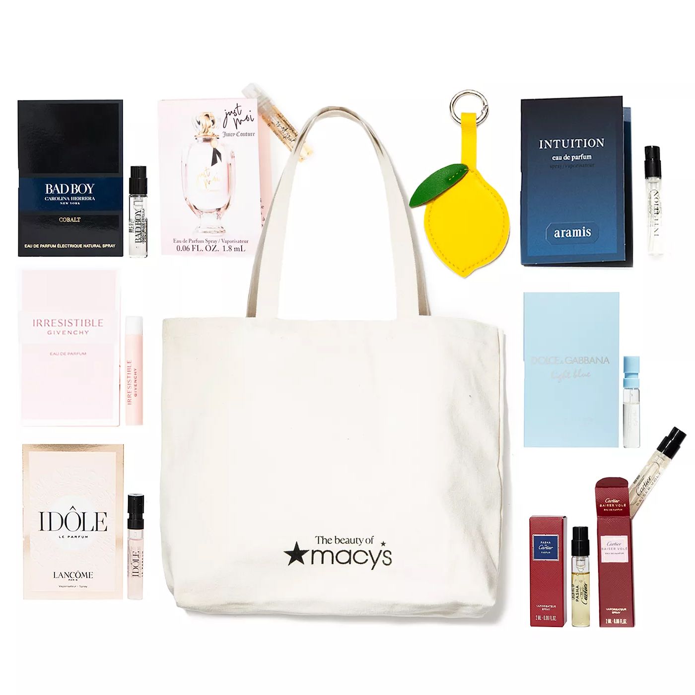 A Macy's tote bag surrounded by numerous fragrance samples, including brands like Bad Boy, Irresistible, Idôle, Intuition, Dolce & Gabbana, and others, plus a lemon-shaped keychain.