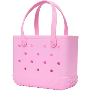 A pink tote bag with a perforated design and sturdy handles, featuring the brand \“Bogg\“ embossed on the lower front.