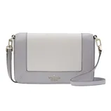 A compact Kate Spade crossbody bag with a chic two-tone design in light grey and cream, featuring gold-tone hardware and an adjustable strap.