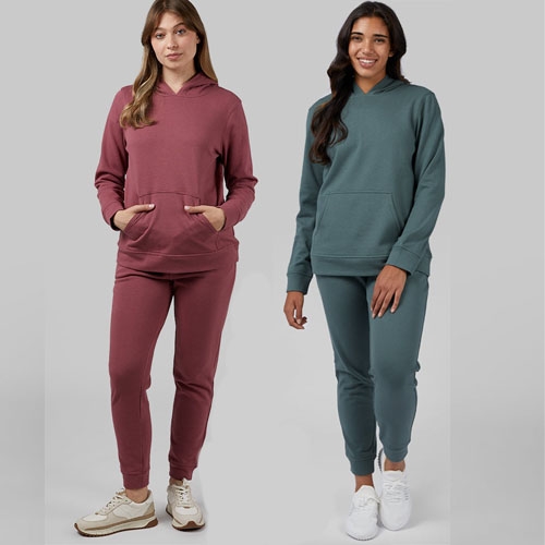 Two women wearing coordinating hoodies and joggers in maroon and teal colors.