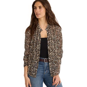 Woman wearing a leopard print blouse over a black top paired with blue jeans and a brown belt.