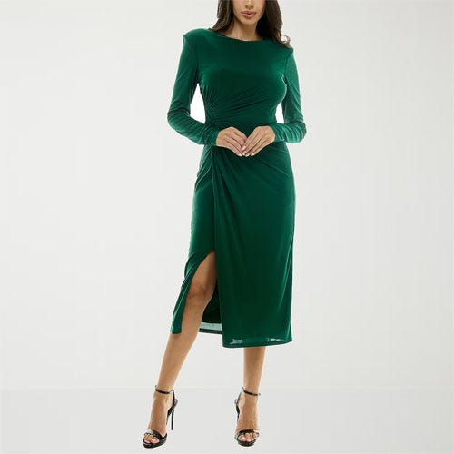 A woman is wearing a long-sleeve green dress with a thigh-high slit, paired with black open-toe heels.