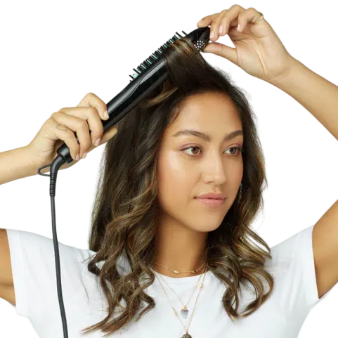 A person is using a heated styling brush on their hair. The brush has a cord and is designed for straightening or styling.