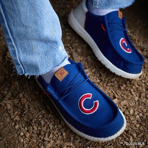 Casual blue shoes with a red and white \“C\“ logo on the top, paired with light blue jeans.